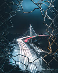 High Angle View Of Light Trails On Bridge Seen Through Hole In Fence - EYF09472
