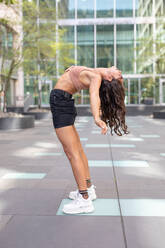 Side View Of Young Woman Bending While Standing In City - EYF09473