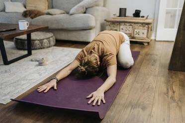 Mid adult woman exercising on mat at home - SMSF00003