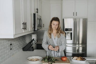 Mid adult woman preparing salad on kitchen counter at home - SMSF00030