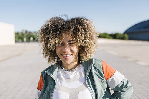 Confident young woman with curly hair during sunny day - XLGF00306