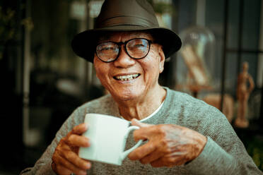 Portrait Of Smiling Senior Man Having Coffee While Sitting In Cafe - EYF09495