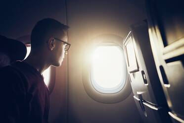 Mann schaut durch ein Flugzeugfenster - EYF09511
