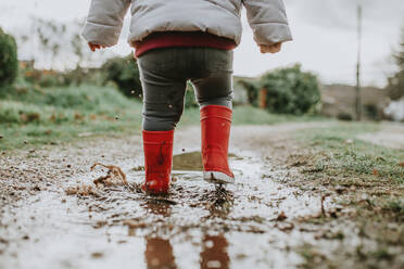 Niedriger Ausschnitt von Baby Girl Walking On Pfütze während der Regenzeit - EYF09528