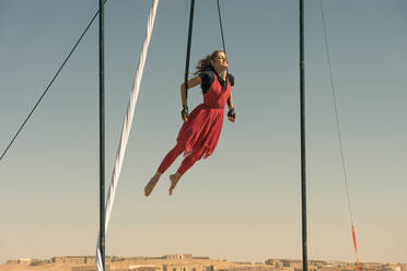 Volle Länge der weiblichen Lufttänzerin tanzen, während hängend von Textil gegen Himmel - EYF09531