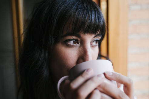 Nahaufnahme einer Frau, die zu Hause Kaffee trinkt - EYF09543