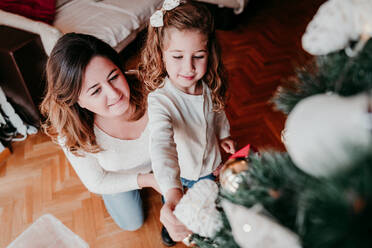 High Angle View Of Mother And Daughter Decorating Christmas Tree At Home - EYF09573