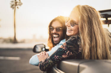 Cheerful Couple Wearing Sunglasses Traveling In Convertible - EYF09577