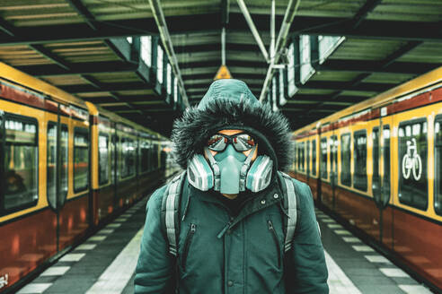 Porträt eines Mannes mit Maske auf dem Bahnsteig eines Bahnhofs - EYF09579