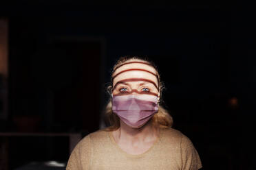Porträt einer jungen Frau mit Maske in der Dunkelkammer - EYF09580