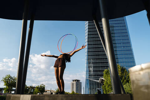 Sporty woman balancing plastic hoops on chest in modern city stock photo