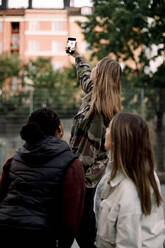 Teenager-Mädchen nimmt Selfie mit Freunden durch Smartphone in der Stadt - MASF18506