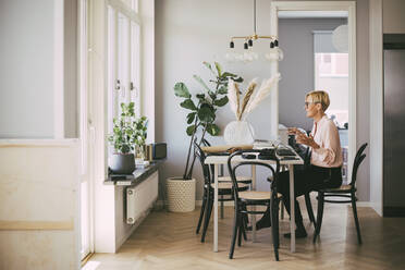 Woman sitting at table having an online meeting working at home - MASF18520