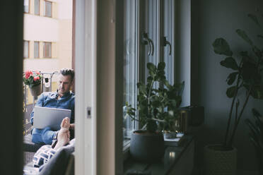 Mann arbeitet am Laptop und entspannt sich auf dem Balkon - MASF18546