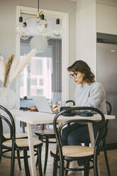 Woman at table working at home - MASF18561