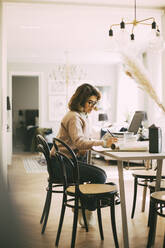 Woman sitting at table working from home - MASF18582