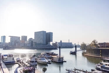 Germany, North Rhine-Westfalia, Dusseldorf, Boats moored in Media Harbor with Stadttor in background - MMAF01340