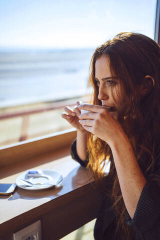 Nachdenkliche Geschäftsfrau trinkt Kaffee im Flughafencafé, lizenzfreies Stockfoto
