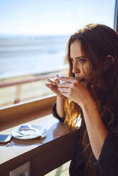 Thoughtful businesswoman drinking coffee at airport cafe - EHF00388