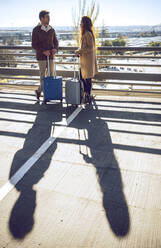 Ein Geschäftspaar unterhält sich auf einem erhöhten Gehweg am Flughafen an einem sonnigen Tag - EHF00403