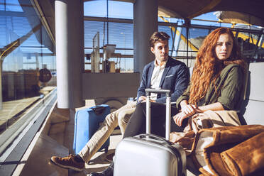 Thoughtful business couple waiting at airport departure area - EHF00438