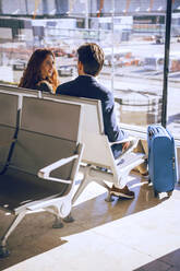 Business couple talking while waiting at airport departure area - EHF00442