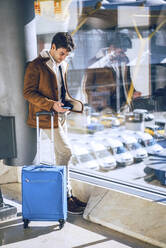 Geschäftsmann mit Smartphone am Fenster im Abflugbereich eines Flughafens - EHF00447