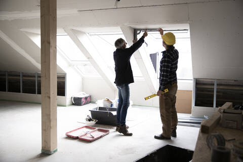 Architekt und Bauarbeiter diskutieren über Fensterrahmen bei der Renovierung eines Hauses, lizenzfreies Stockfoto