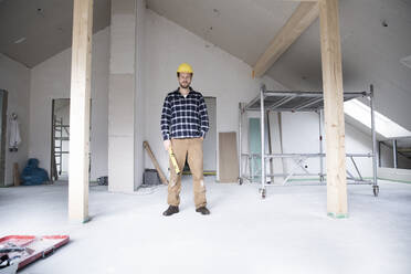 Confident construction worker standing at renovating home - MJFKF00437