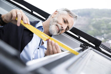 Nahaufnahme eines männlichen Architekten, der ein Fenster vermisst - MJFKF00439