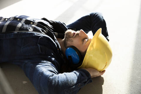 Close-up of construction worker with hands behind head sleeping on floor in renovating house stock photo