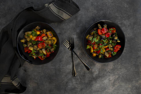 Zwei Schüsseln veganer Salat mit Auberginen, Paprika und Petersilie, unter Rühren gebraten - LVF08978