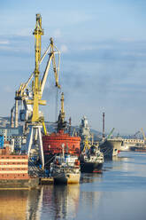 Russland, Murmansk, Industrieschiffe und Kräne im Hafenbecken - RUNF03772