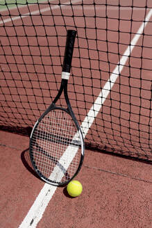 Tennisschläger mit Ball am Netz auf einem Platz in der Sonne - EGAF00408