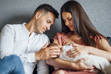 Father looking at baby boy being breastfed by mother at home - OCMF01443