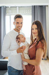 Happy parents carrying baby boy at home - OCMF01454