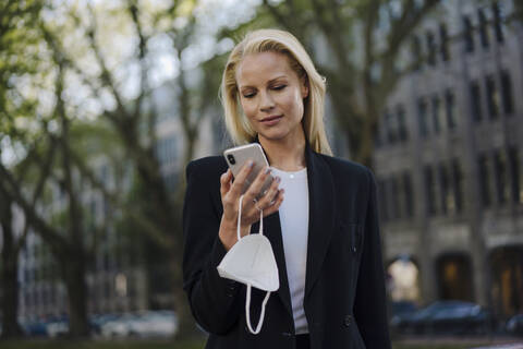 Beautiful businesswoman using mobile phone while standing in city stock photo