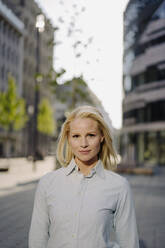 Confident beautiful blond businesswoman standing in city - JOSEF00973