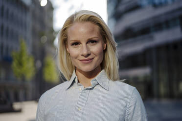 Close-up of beautiful blond businesswoman smiling in city - JOSEF01004