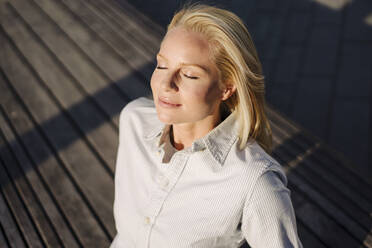 Blond female professional soaking sunlight in city - JOSEF01030