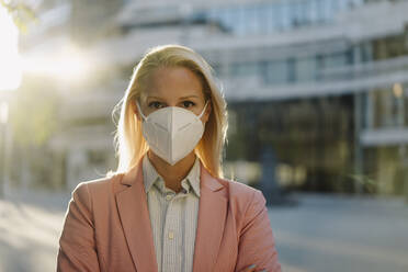 Blond female professional wearing protective face mask in financial district during coronavirus - JOSEF01077