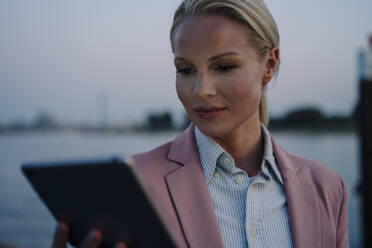 Nahaufnahme einer schönen Unternehmerin, die ein digitales Tablet gegen den Himmel bei Sonnenuntergang benutzt - JOSEF01102