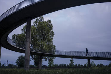 Geschäftsmann zu Fuß auf einer abgelegenen Brücke in der Abenddämmerung - JOSEF01161