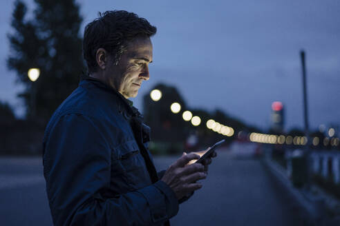 Mature man using tablet on a promenade at dusk - JOSEF01172