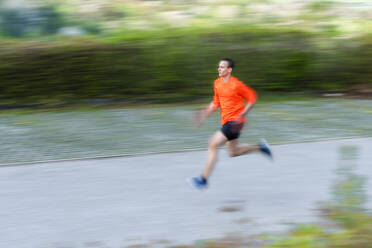 Blurred motion of young man running on footpath - STSF02552