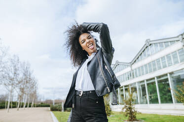 Cheerful young woman sticking out tongue while standing against sky - KIJF03165