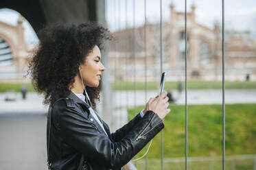 Junge Frau mit Afrofrisur beim Fotografieren mit Smartphone - KIJF03183