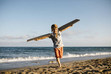 Junge läuft mit Pappflügeln und Fliegermütze am Strand - JRFF04562