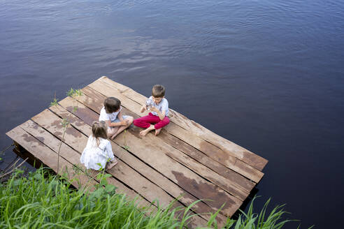 Children playing on pier over lake in forest - VPIF02568