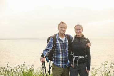 Two hikers, man and woman, embracing on a coastal path - CUF55533